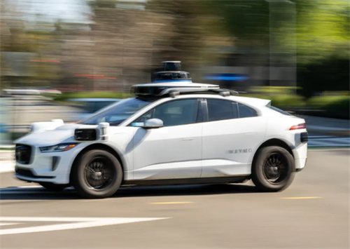 A Waymo self-driving car with roof-mounted sensors, representing the company's robotaxi fleet.