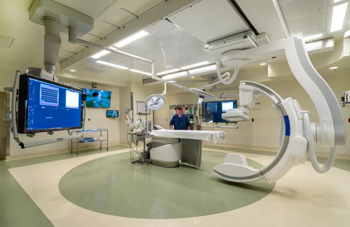 Modern hybrid operating room equipped with C-arm fluoroscopy system and medical monitors